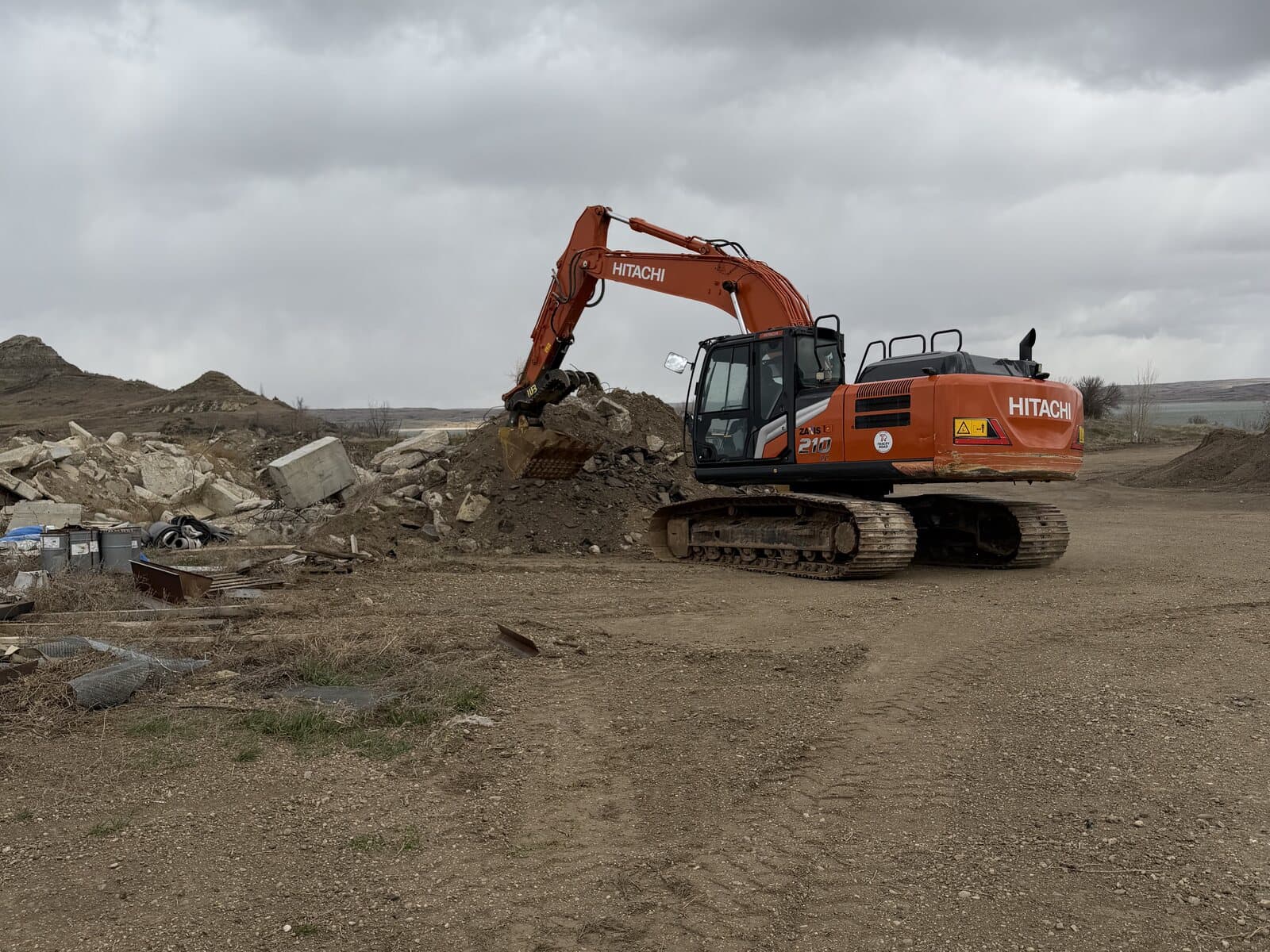 A tracked excavator working a pile of broken concrete
