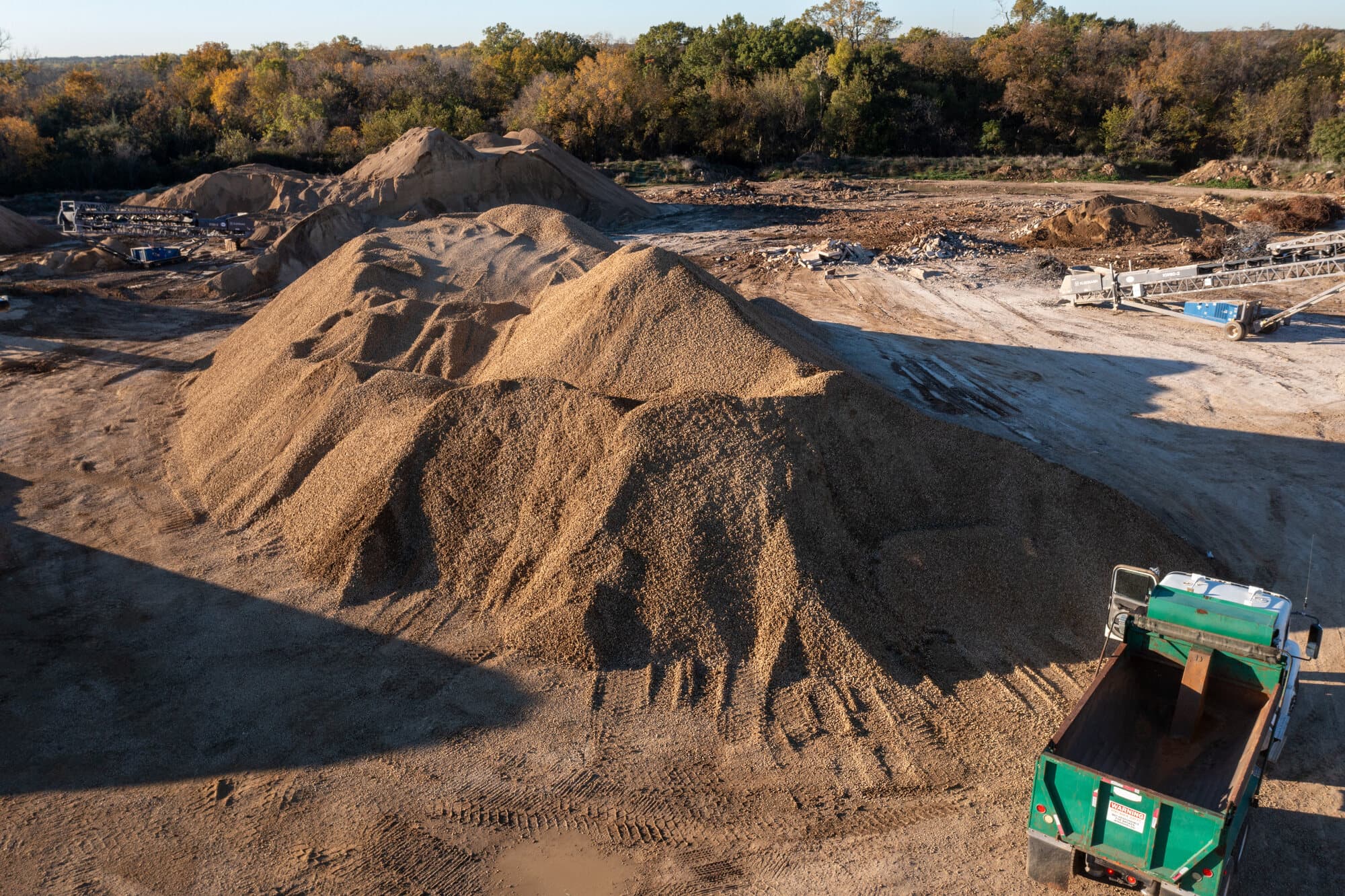 A screened topsoil stockpile beside a screening plant